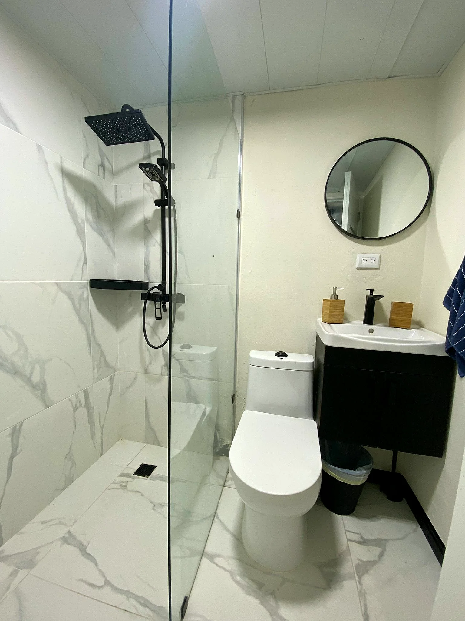 Baño de mármol con ducha de vidrio en Solano Apartments