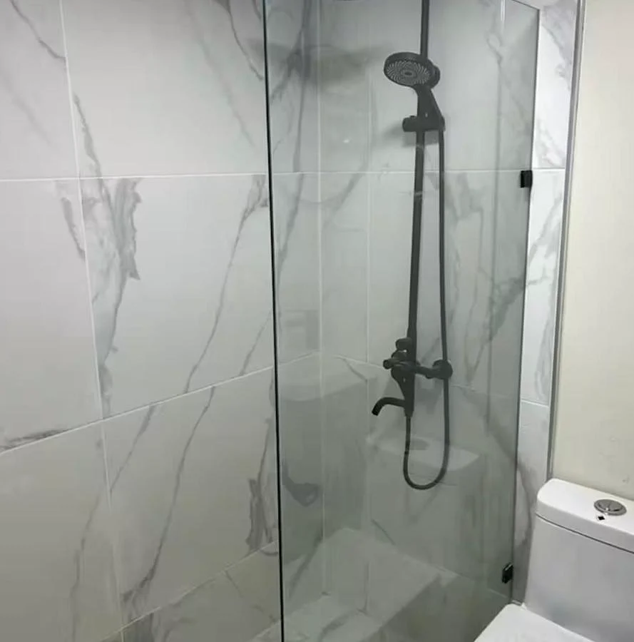 Baño moderno de Solano Apartments con ducha de cristal y azulejos blancos